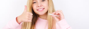 Blonde girl holding clear aligners