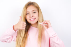 Blonde girl holding clear aligners