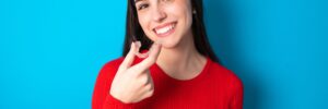Woman holding clear aligners on blue background