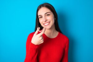 Woman holding clear aligners on blue background