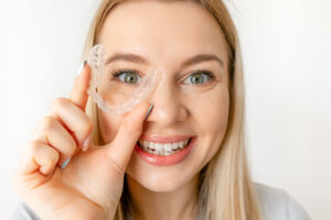 Blonde woman holding clear aligner