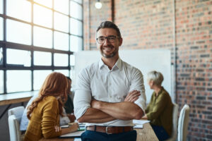 Businessman standing smiling in front of coworkers