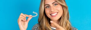 MODEL holding an invisible aligner and pointing at it. Dental healthcare and confidence concept.